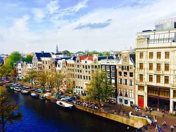 Buildings by canal against sky in city