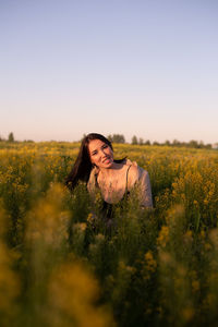 Woman with arms raised on field against sky