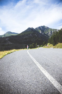 Man on road by mountains against sky