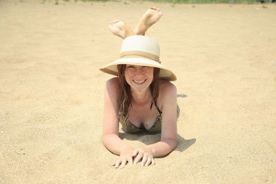 Portrait of smiling young woman lying on sand