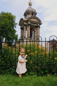 Girl standing in front of building against cloudy sky