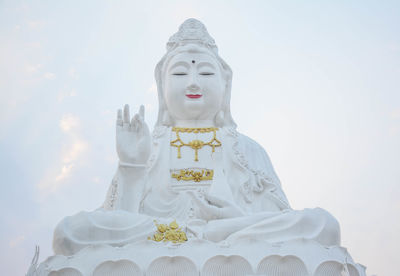 Low angle view of statue against temple building against sky