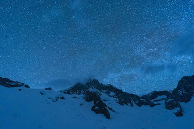 Scenic view of snowcapped mountains against sky at night