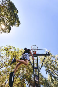 Low angle view of man playing basketball against clear sky