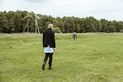 Rear view of man walking on field