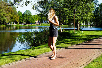 Full length of woman standing on footpath by lake
