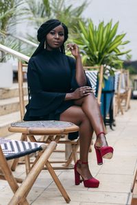 Portrait of woman sitting on chair at sidewalk cafe