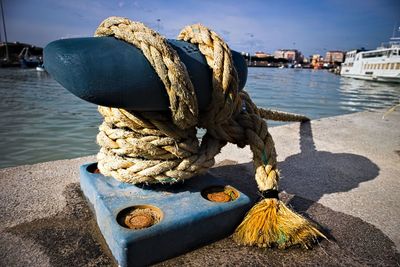 Close-up of ropes tied to cleat at harbor