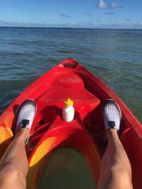 Low section of woman holding umbrella at sea shore