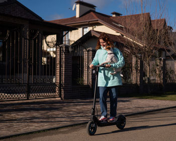 Full length of woman riding push scooter