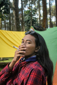 Side view of young woman blowing bubbles in forest