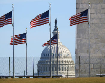 Flags surrounding the washington monument with the us capitol dome in the background.