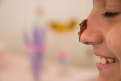 Close-up of smiling girl with food on nose