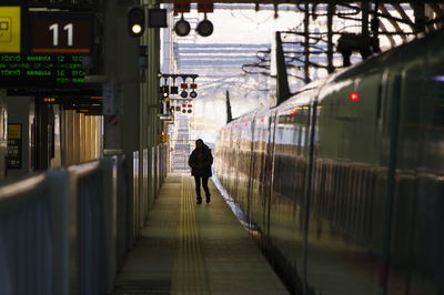 Rear view of man walking on railroad station platform