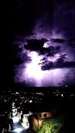 Storm clouds over illuminated buildings in city at night