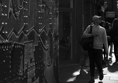 Rear view of man walking on street amidst buildings