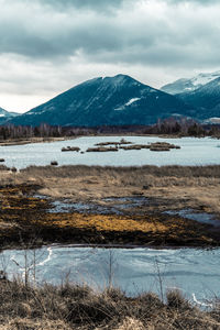 Scenic view of lake by snowcapped mountains against sky