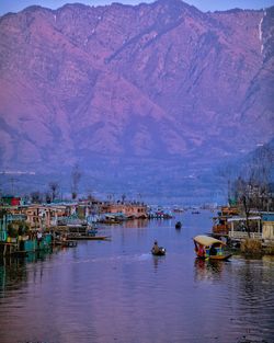 Sailboats moored on lake by buildings against mountains