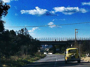 Cars on road against cloudy sky