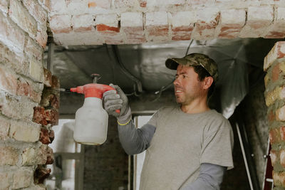 A young man sprays water from a spray bottle onto the bricks in the doorway.