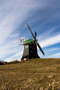Traditional windmill on field against sky