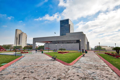 People in park by buildings against sky in city