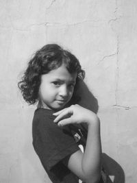 Girl looking away while standing against wall