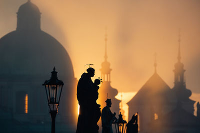 Statues on charles bridge against urban skyline with church and towers in prague.