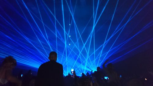 Silhouette people enjoying laser show