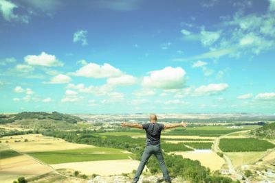 Rear view of man standing on landscape against sky