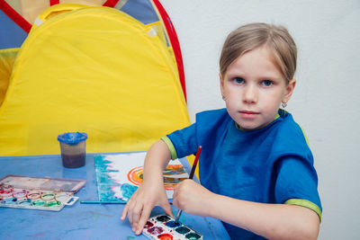 Portrait of girl painting by tent