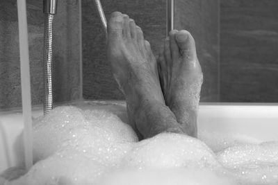 Low section of person relaxing in bathtub