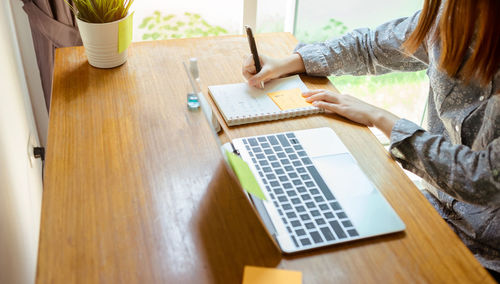 Midsection of woman using mobile phone while sitting on table