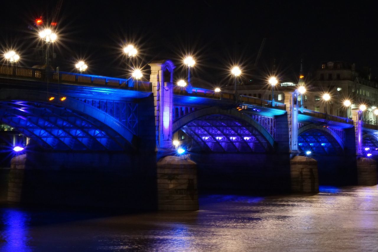 ILLUMINATED BRIDGE IN CITY AGAINST BLUE SKY AT NIGHT