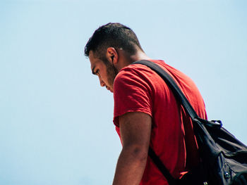 Side view of young man standing against clear sky