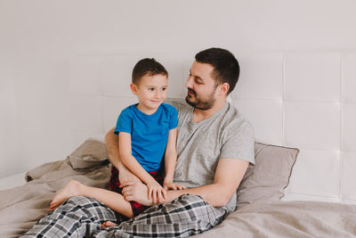 Son sitting on father's lap at home