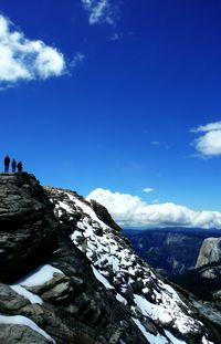 Tourists on mountain against cloudy sky