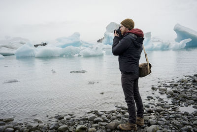 Man taking a photo at jokulsarlon glacier lagoon at dusk