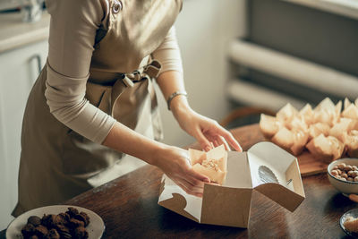 Woman bakery shop owner hold box for customer order. chef baking pastry, cake in kitchen. delivery