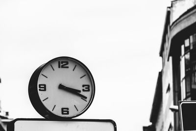 Low angle view of clock against sky