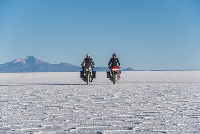 Two men riding touring motorbike's on the salt flats of uyuni