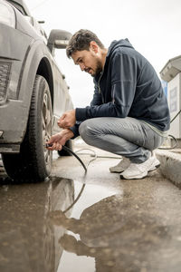 Man filling air in tire at gas station