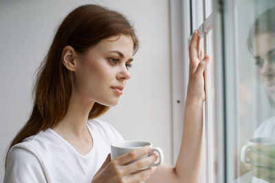 Close-up of woman looking through window