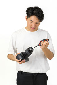 Young man looking away while standing against white background