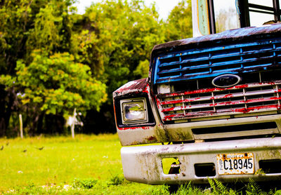 Close-up of vintage car on grass against trees