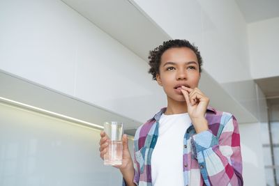 Portrait of young woman standing against wall