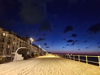 Illuminated road against sky at night