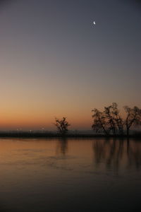 Scenic view of lake against clear sky at sunset