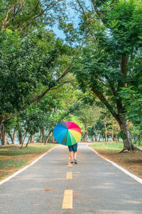 Rear view of woman with umbrella on road