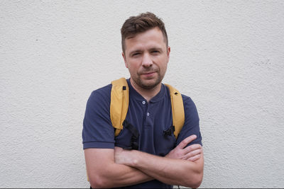 Portrait of young man standing against wall